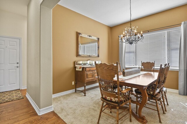 dining area featuring baseboards, a chandelier, and light wood finished floors