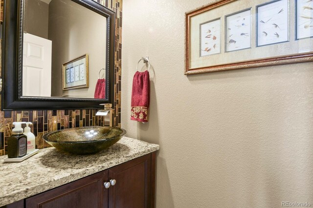 bathroom featuring vanity, a textured wall, and backsplash