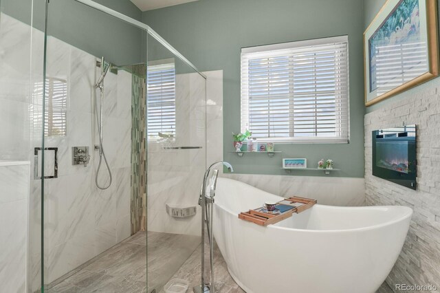 bathroom featuring a marble finish shower and a freestanding bath