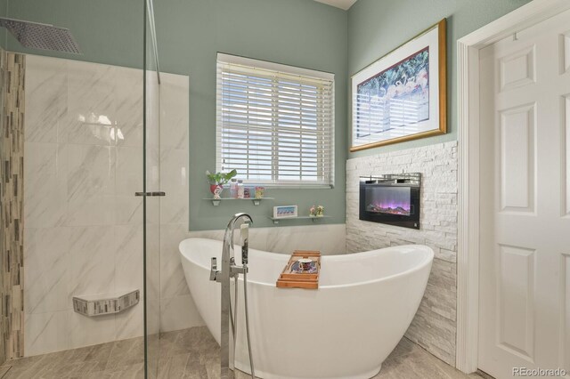 full bathroom featuring a stone fireplace, a walk in shower, and a freestanding bath