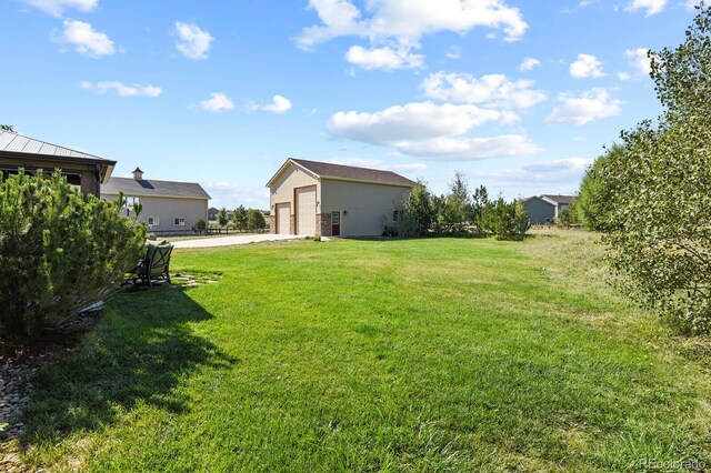 view of yard with a garage, an outdoor structure, and concrete driveway