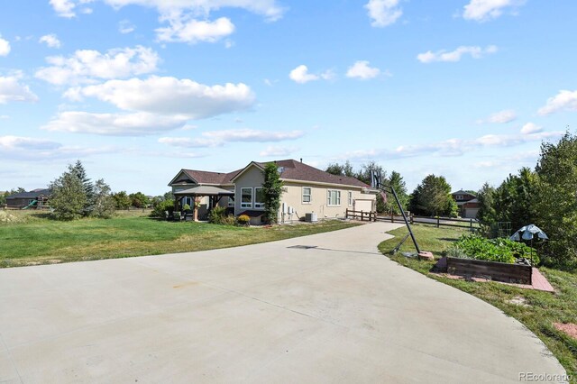 view of front facade featuring stucco siding, a front lawn, fence, and driveway