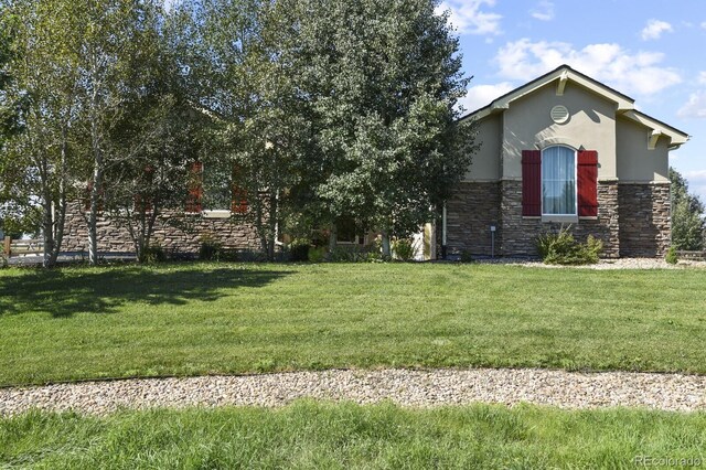 view of front of property featuring stucco siding, a front yard, and stone siding