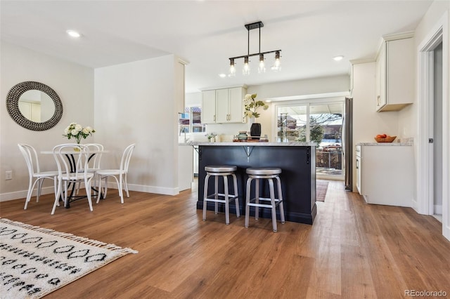 kitchen with decorative light fixtures, white cabinetry, a kitchen island, and light wood-type flooring