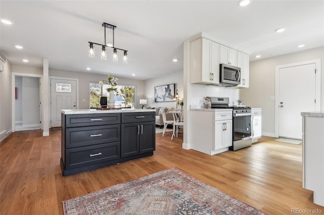 kitchen with pendant lighting, white cabinetry, appliances with stainless steel finishes, and light hardwood / wood-style flooring