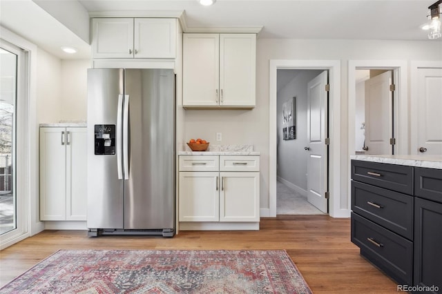 kitchen featuring stainless steel refrigerator with ice dispenser, white cabinetry, and light hardwood / wood-style floors