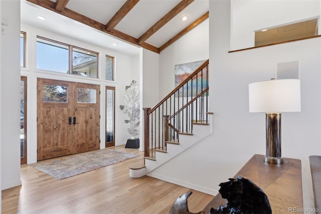 entryway featuring beam ceiling, high vaulted ceiling, and light hardwood / wood-style flooring