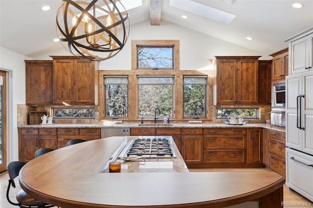 kitchen featuring lofted ceiling with skylight, sink, hanging light fixtures, stainless steel appliances, and backsplash