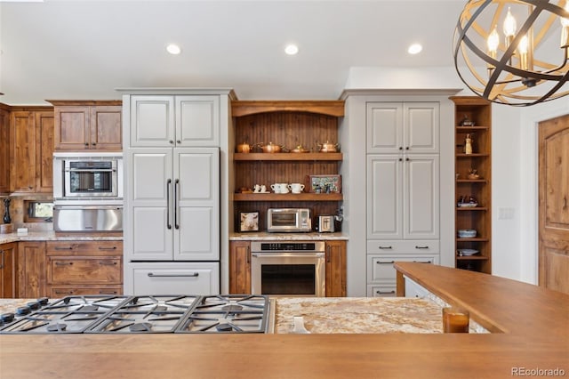 kitchen with gas cooktop, white cabinetry, stainless steel oven, decorative light fixtures, and a chandelier