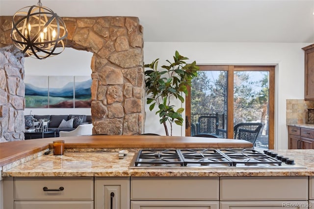 kitchen with light stone counters, decorative light fixtures, a chandelier, and stainless steel gas stovetop