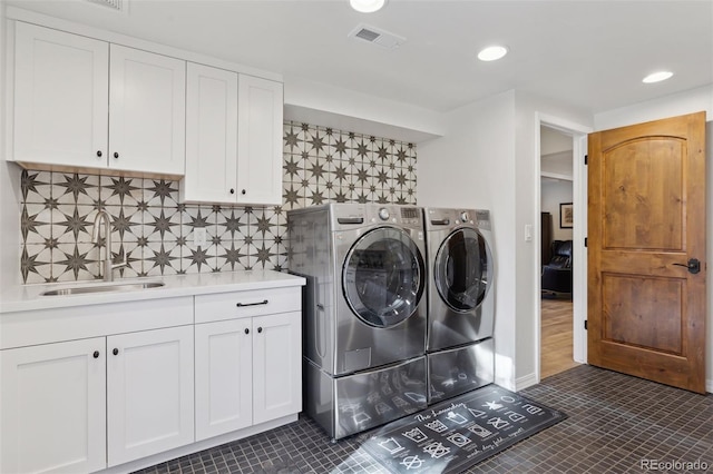 clothes washing area with sink, cabinets, washing machine and clothes dryer, and dark tile patterned flooring