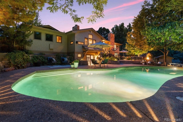 pool at dusk with a patio