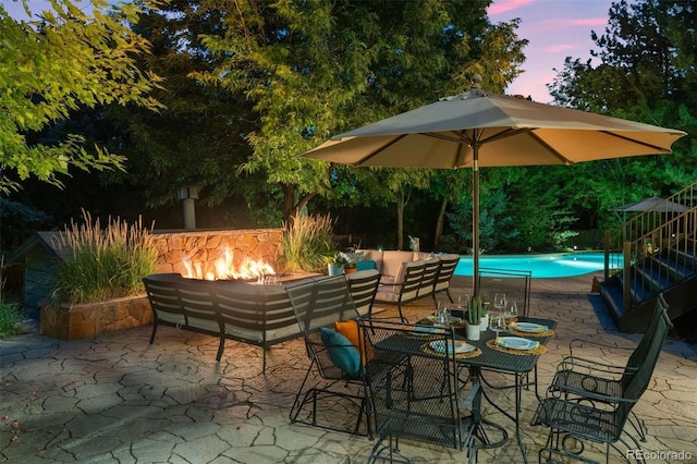 patio terrace at dusk with an outdoor living space with a fire pit