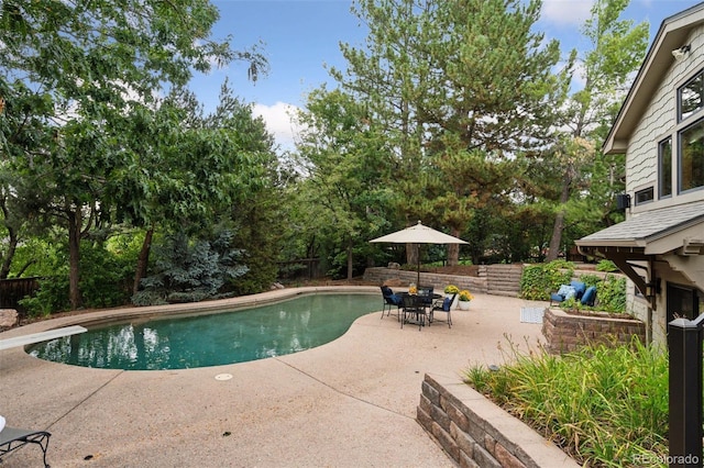 view of pool with a diving board and a patio area