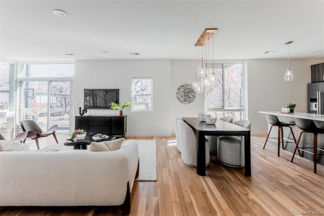 living room with visible vents, a wall of windows, light wood-style flooring, and baseboards