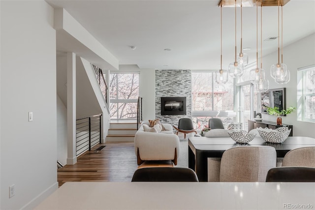 living room featuring stairs, wood finished floors, a tile fireplace, and a healthy amount of sunlight