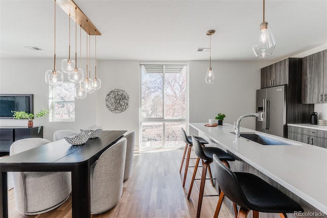 kitchen featuring high quality fridge, a breakfast bar area, a sink, light wood-style floors, and light countertops