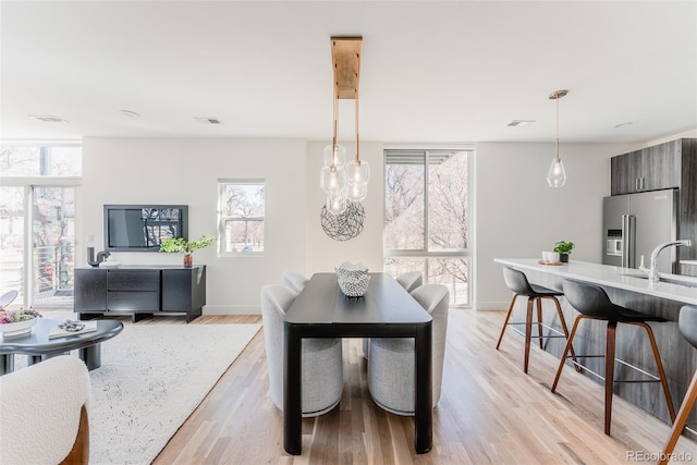 dining room with light wood finished floors, baseboards, and visible vents