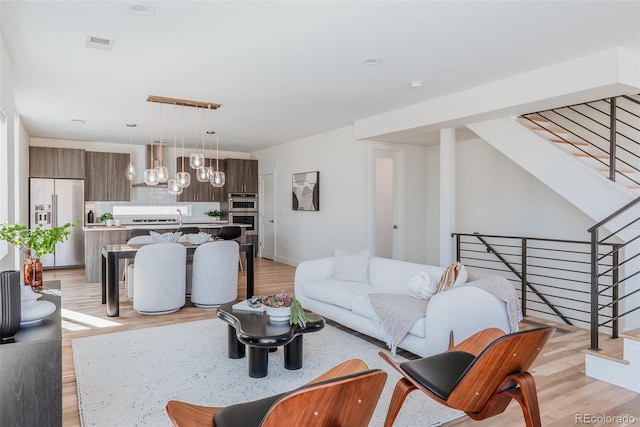 living area with visible vents, stairway, and light wood-style flooring