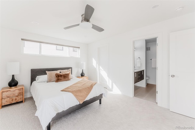 bedroom with ceiling fan, ensuite bath, visible vents, and light colored carpet