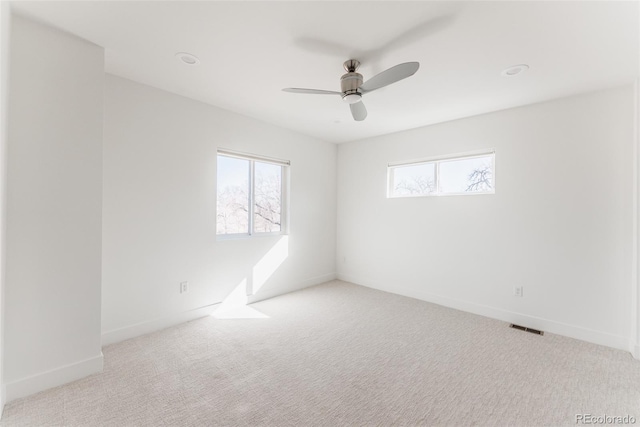 carpeted spare room with a ceiling fan, visible vents, and baseboards