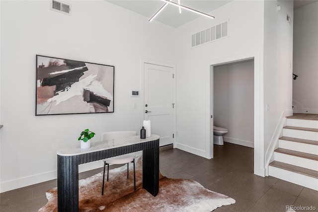 home office with visible vents, a towering ceiling, and baseboards