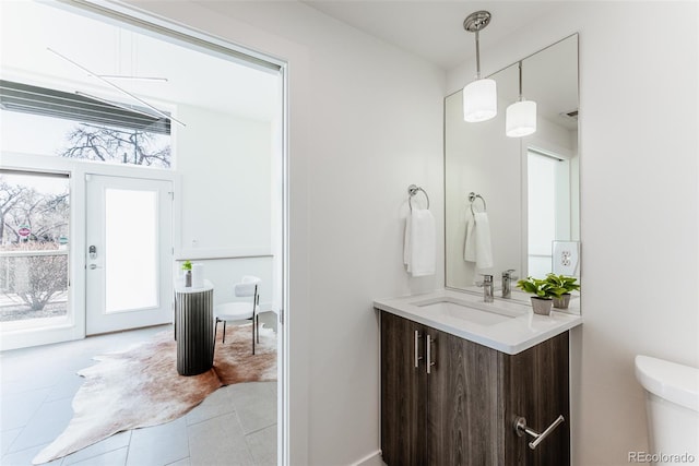 half bathroom featuring tile patterned flooring, a healthy amount of sunlight, vanity, and toilet