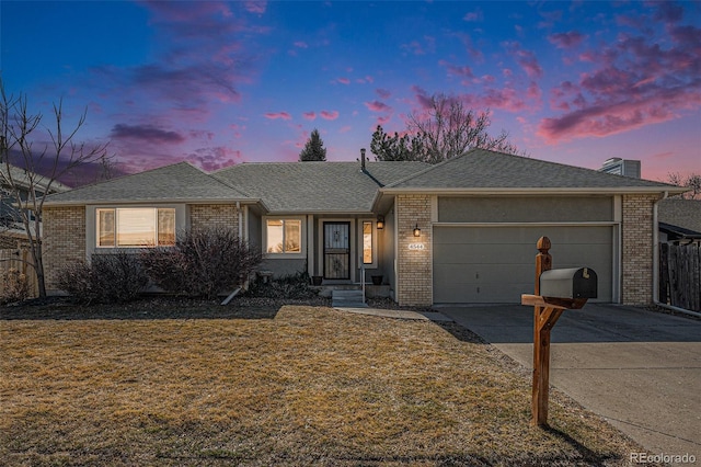 single story home featuring a yard, concrete driveway, an attached garage, a shingled roof, and brick siding