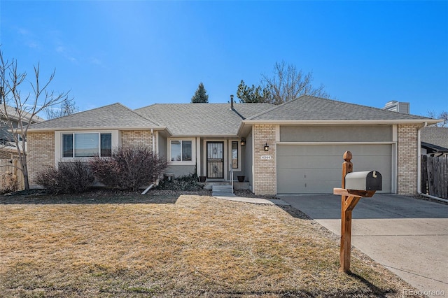 ranch-style home featuring brick siding, a shingled roof, concrete driveway, a front yard, and an attached garage