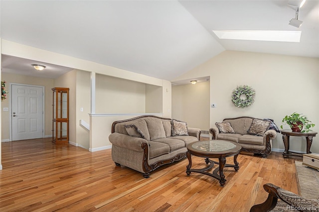 living room with light wood-type flooring, lofted ceiling with skylight, and baseboards