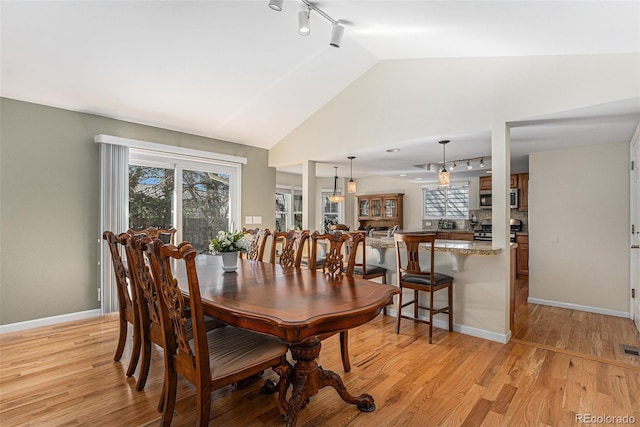 dining space featuring lofted ceiling, light wood-style flooring, plenty of natural light, and baseboards