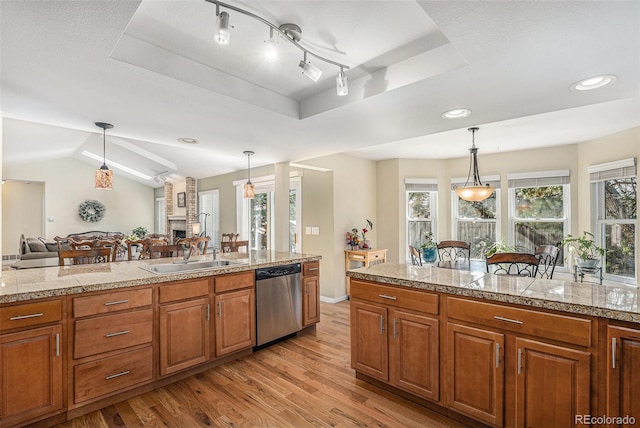 kitchen with a sink, tile counters, pendant lighting, dishwasher, and a raised ceiling