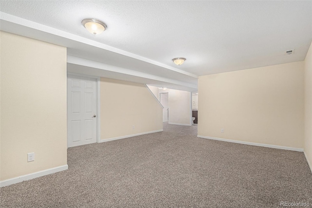 finished below grade area with baseboards, carpet floors, and a textured ceiling