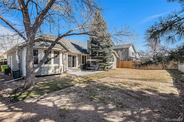 rear view of house with fence, stucco siding, entry steps, a patio area, and a lawn