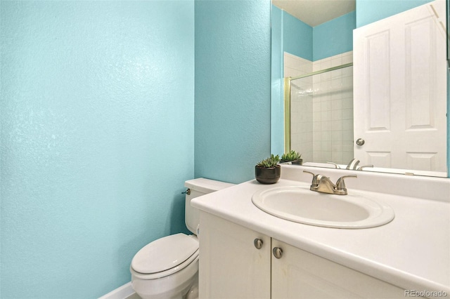 bathroom with vanity, toilet, and tiled shower