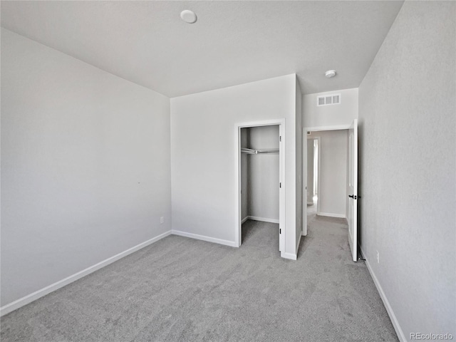 unfurnished bedroom with light carpet and a closet