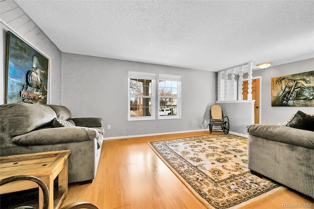 living area featuring wood finished floors, baseboards, and a textured ceiling