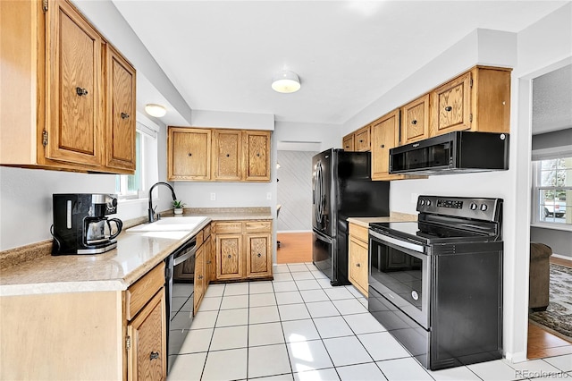 kitchen with black appliances, light tile patterned floors, light countertops, and a sink