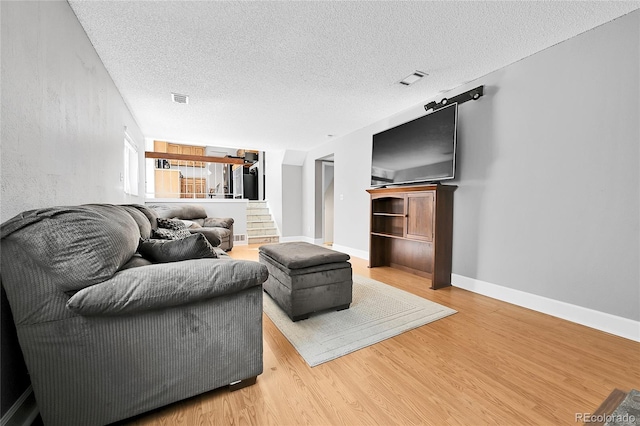 living room with visible vents, a textured ceiling, stairs, and wood finished floors