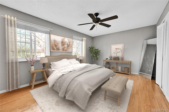 bedroom featuring baseboards, a textured ceiling, wood finished floors, and a ceiling fan