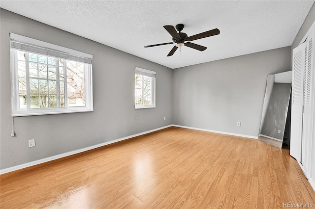 spare room with baseboards, light wood-style floors, a ceiling fan, and a textured ceiling