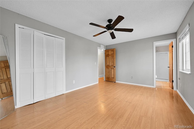 unfurnished bedroom featuring a closet, baseboards, a textured ceiling, and light wood finished floors