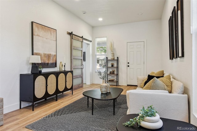 living area featuring a barn door, light wood-type flooring, baseboards, and recessed lighting