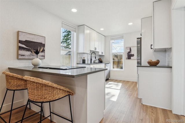 kitchen with dark countertops, black electric stovetop, plenty of natural light, white cabinets, and recessed lighting