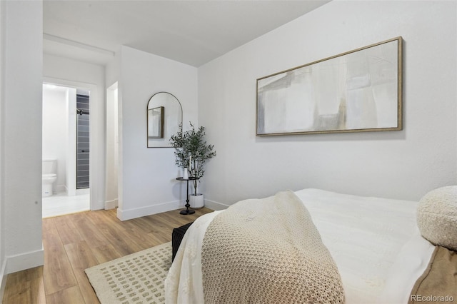 bedroom featuring wood finished floors, baseboards, and connected bathroom