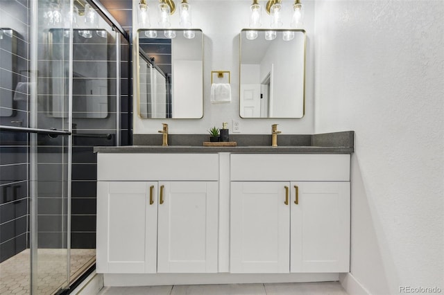 bathroom with double vanity, a tile shower, and a textured wall