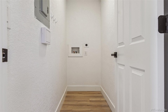 washroom featuring wood finished floors, washer hookup, baseboards, electric dryer hookup, and a textured wall
