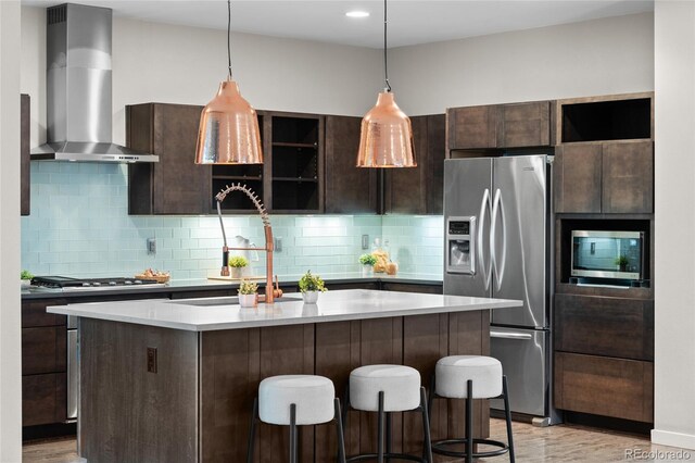 3384 Cranston Cir, Highlands Ranch, CO 80126 - kitchen featuring appliances with stainless steel finishes, wall chimney exhaust hood, dark brown cabinetry, a kitchen bar, and recessed lighting
