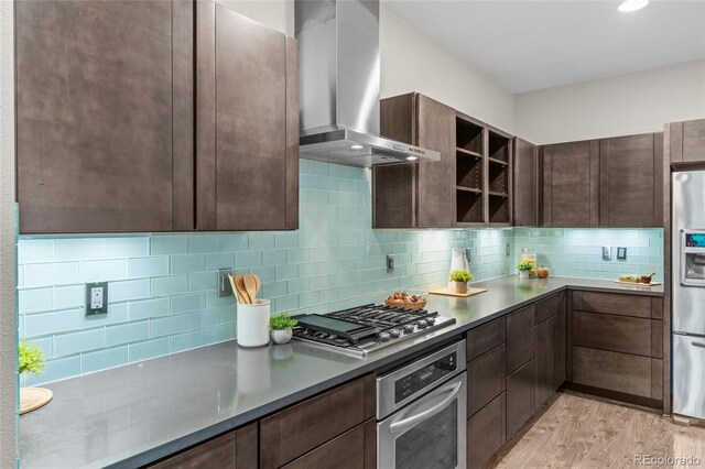 3384 Cranston Cir, Highlands Ranch, CO 80126 - kitchen with stainless steel appliances, wall chimney exhaust hood, dark brown cabinetry, and light wood-style floors