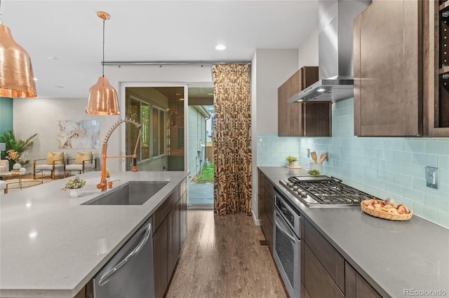 3384 Cranston Cir, Highlands Ranch, CO 80126 - kitchen featuring wall chimney range hood, a sink, appliances with stainless steel finishes, wood finished floors, and decorative backsplash